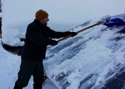 Un volontario spala la neve dai pannelli solari della malga in Valtrigona, febbraio 2026